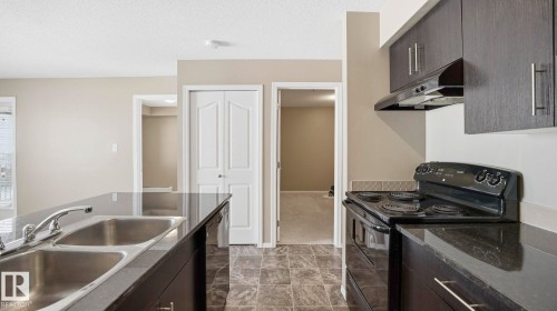 Kitchen with black appliances, a textured ceiling, dark wood finish cabinets, modern cabinets, and dark cabinets - 319 274 Mcconachie Drive, Edmonton, AB - Indoor Photo Showing Kitchen With Double Sink