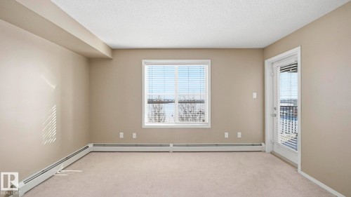 Spare room featuring a baseboard radiator, light colored carpet, plenty of natural light, and a textured ceiling - 319 274 Mcconachie Drive, Edmonton, AB - Indoor Photo Showing Other Room