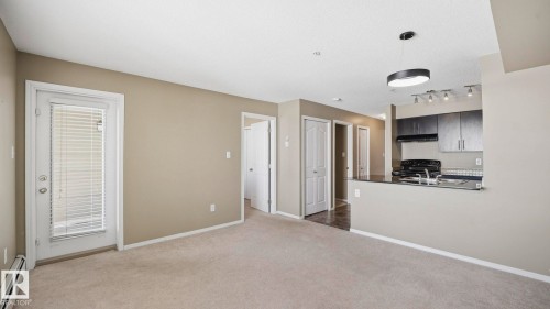 Kitchen with baseboard heating, dark countertops, black range with electric cooktop, dark carpet, and a textured ceiling - 319 274 Mcconachie Drive, Edmonton, AB - Indoor Photo Showing Other Room