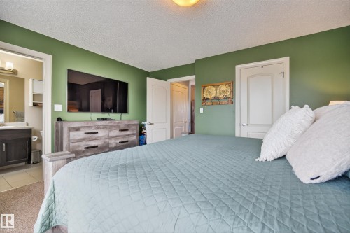 Bedroom featuring a textured ceiling, light carpet, and connected bathroom - 7074 Cardinal Way, Edmonton, AB - Indoor Photo Showing Bedroom