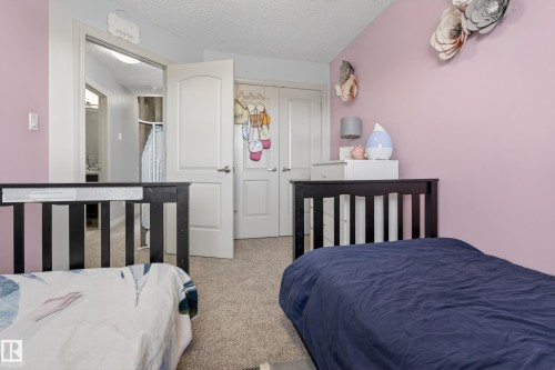 Carpeted bedroom with a textured ceiling and a closet - 7074 Cardinal Way, Edmonton, AB - Indoor Photo Showing Bedroom