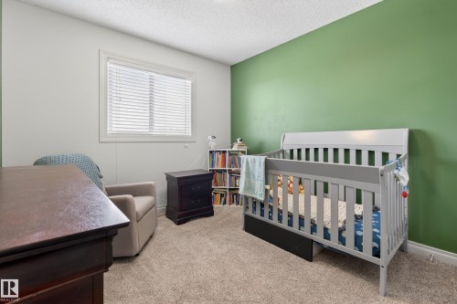 Carpeted bedroom featuring a nursery area and a textured ceiling - 7074 Cardinal Way, Edmonton, AB - Indoor Photo Showing Bedroom