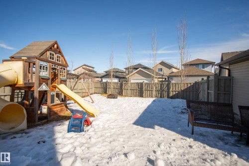 Snow covered playground with a residential view, a playground, and a fenced backyard - 7074 Cardinal Way, Edmonton, AB - Outdoor