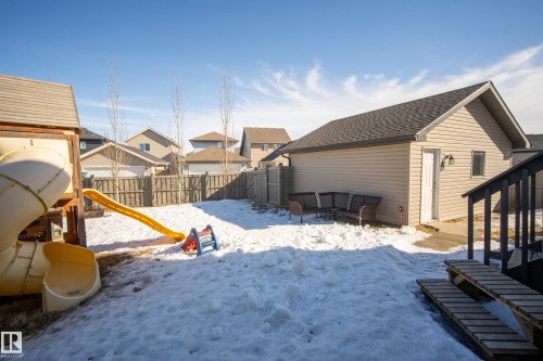 Yard covered in snow with a residential view, a fenced backyard, and a playground - 7074 Cardinal Way, Edmonton, AB - Outdoor With Exterior