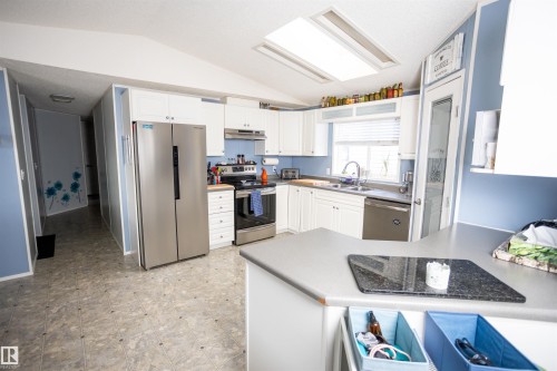 Well-appointed kitchen featuring white cabinetry, stainless steel appliances, a double basin sink, and a skylight providing natural light - 41 Graywood Cove, Stony Plain, AB - Indoor Photo Showing Kitchen With Stainless Steel Kitchen With Double Sink