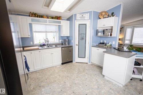 The kitchen features white cabinetry, a double basin sink, and a stainless steel dishwasher - 41 Graywood Cove, Stony Plain, AB - Indoor Photo Showing Kitchen With Double Sink