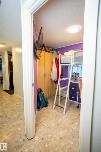 This room features patterned tile flooring, a built-in wooden wardrobe, and a prominent ceiling light fixture - 41 Graywood Cove, Stony Plain, AB - Indoor