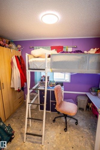 The room features a loft bed with a ladder, wood-look cabinetry, and patterned floor tiles - 41 Graywood Cove, Stony Plain, AB - Indoor With Storage