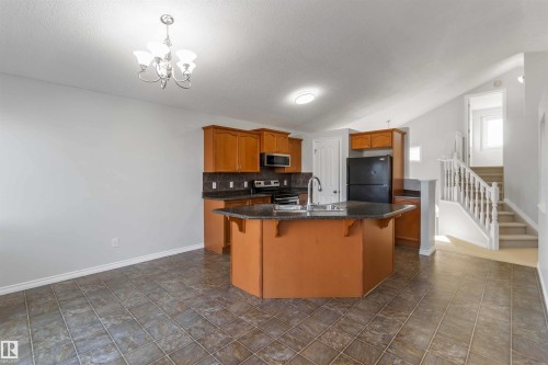 Kitchen with stainless steel appliances, a center island with sink, a kitchen breakfast bar, tasteful backsplash, and hanging lights - 20604 48 Avenue, Edmonton, AB - Indoor Photo Showing Kitchen