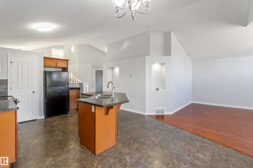Kitchen featuring dark countertops, an island with sink, freestanding refrigerator, and a kitchen breakfast bar - 20604 48 Avenue, Edmonton, AB - Indoor Photo Showing Kitchen With Double Sink