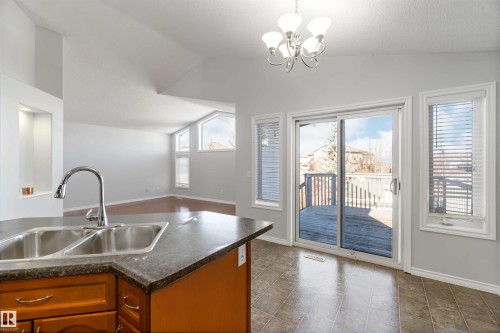 Kitchen with dark countertops, wood finish cabinetry, vaulted ceiling, and hanging lights - 20604 48 Avenue, Edmonton, AB - Indoor Photo Showing Kitchen With Double Sink