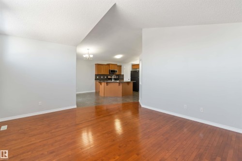Unfurnished living room with dark wood finished floors, a chandelier, and a textured ceiling - 20604 48 Avenue, Edmonton, AB - Indoor Photo Showing Other Room