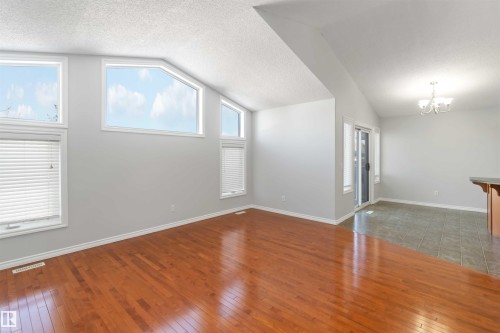 Empty room featuring dark wood-style floors, suspended lighting, and plenty of natural light - 20604 48 Avenue, Edmonton, AB - Indoor Photo Showing Other Room