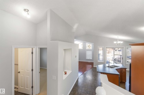 Kitchen featuring a kitchen island with sink, suspended lighting, dark countertops, and wood finish cabinetry - 20604 48 Avenue, Edmonton, AB - Indoor Photo Showing Other Room