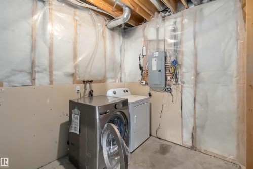 Laundry area with electric panel, concrete flooring, and washing machine and clothes dryer - 20604 48 Avenue, Edmonton, AB - Indoor Photo Showing Laundry Room