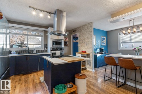 Kitchen with island exhaust hood, light countertops, a center island, light wood-style floors, and track lighting - 14 Lester Crescent, St. Albert, AB - Indoor Photo Showing Kitchen With Upgraded Kitchen