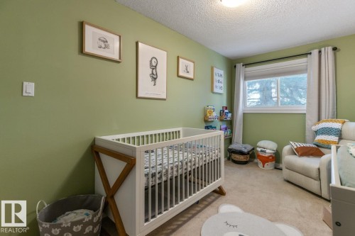 Bedroom with a nursery area, light carpet, and a textured ceiling - 14 Lester Crescent, St. Albert, AB - Indoor Photo Showing Bedroom