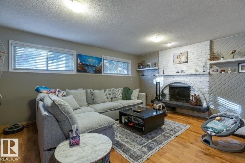 Living room featuring hardwood / wood-style floors, plenty of natural light, a fireplace, and a textured ceiling - 14 Lester Crescent, St. Albert, AB - Indoor Photo Showing Living Room With Fireplace