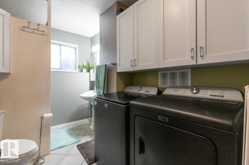 Laundry area featuring light tile patterned flooring, independent washer and dryer, and a textured ceiling - 14 Lester Crescent, St. Albert, AB - Indoor Photo Showing Laundry Room