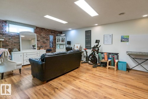 Living room featuring light wood-type flooring and brick wall - 14 Lester Crescent, St. Albert, AB - Indoor