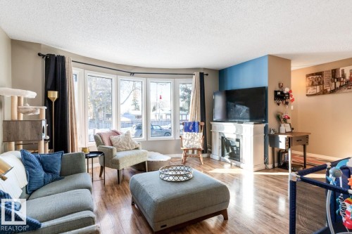 Living area featuring hardwood / wood-style floors, a textured ceiling, and a glass covered fireplace - 14 Lester Crescent, St. Albert, AB - Indoor Photo Showing Living Room