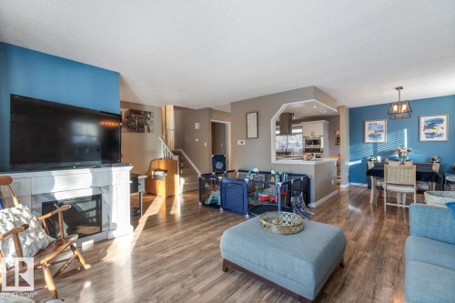 Living area with dark wood-type flooring, a glass covered fireplace, and a textured ceiling - 14 Lester Crescent, St. Albert, AB - Indoor Photo Showing Living Room With Fireplace