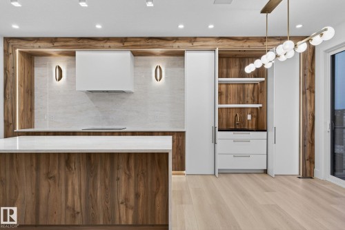 Kitchen with modern cabinets, light stone countertops, wood finish cabinetry, light wood-style floors, and range hood - 8765 Mayday Lane, Edmonton, AB - Indoor Photo Showing Other Room