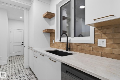 Kitchen with open shelves, white cabinets, tasteful backsplash, light stone countertops, and dishwashing machine - 8765 Mayday Lane, Edmonton, AB - Indoor Photo Showing Kitchen