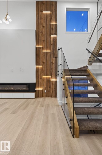 Staircase with wood finished floors and a glass covered fireplace - 8765 Mayday Lane, Edmonton, AB - Indoor Photo Showing Other Room
