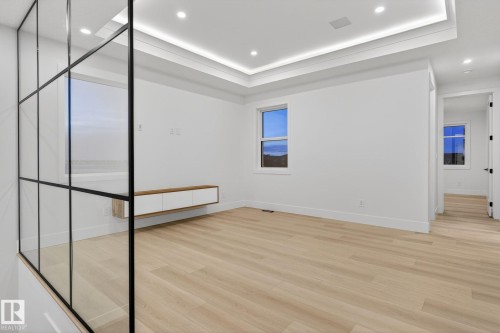 Empty room featuring light wood-style floors, recessed lighting, and a raised ceiling - 8765 Mayday Lane, Edmonton, AB - Indoor Photo Showing Other Room