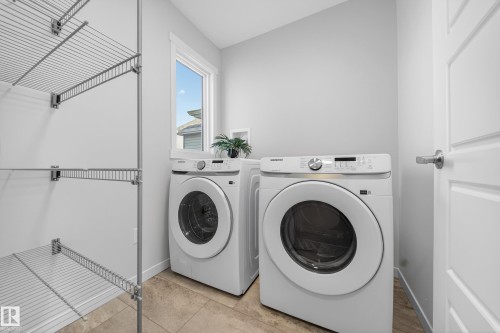 Laundry area with washer and dryer, vaulted ceiling, and light tile patterned floors - 20723 24 Avenue, Edmonton, AB - Indoor Photo Showing Laundry Room