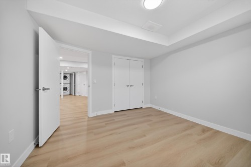 Unfurnished bedroom featuring stacked washer / dryer, light wood-style floors, and a closet - 20723 24 Avenue, Edmonton, AB - Indoor Photo Showing Other Room