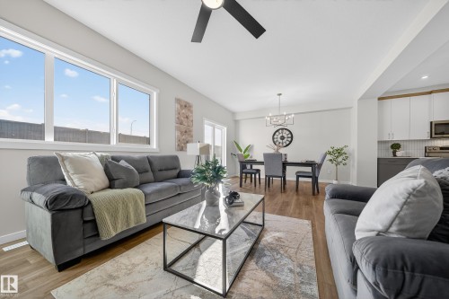 Living area with ceiling fan, light wood finished floors, and suspended lighting - 20723 24 Avenue, Edmonton, AB - Indoor Photo Showing Living Room