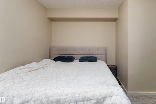Carpeted bedroom featuring a textured ceiling and baseboards - 205 340 Windermere Road, Edmonton, AB - Indoor Photo Showing Bedroom