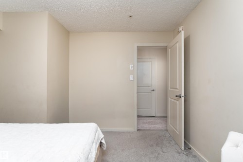Bedroom with light colored carpet and a textured ceiling - 205 340 Windermere Road, Edmonton, AB - Indoor Photo Showing Bedroom
