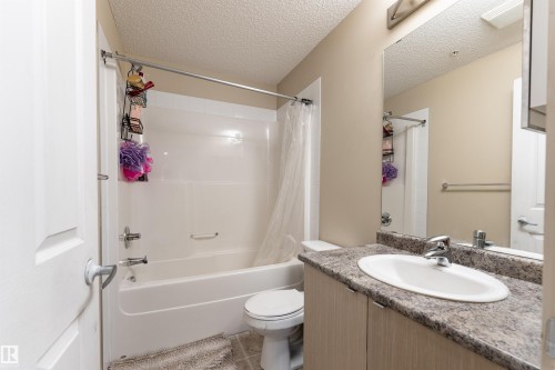 Bathroom with vanity, a textured ceiling, shower / tub combo, and light tile patterned flooring - 205 340 Windermere Road, Edmonton, AB - Indoor Photo Showing Bathroom