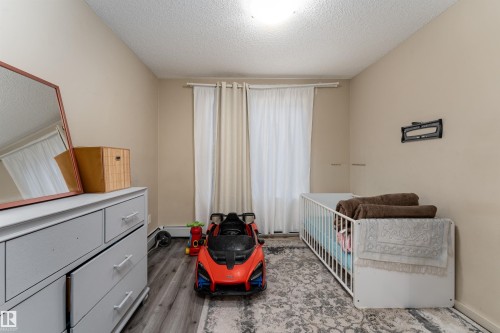 Bedroom with a nursery area, a textured ceiling, and light wood-type flooring - 205 340 Windermere Road, Edmonton, AB - Indoor Photo Showing Other Room