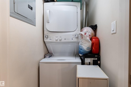 Laundry room with electric panel and stacked washer / dryer - 205 340 Windermere Road, Edmonton, AB - Indoor Photo Showing Laundry Room