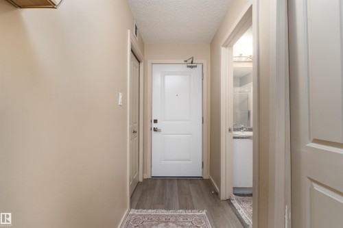 Doorway featuring a textured ceiling and wood finished floors - 205 340 Windermere Road, Edmonton, AB - Indoor Photo Showing Other Room