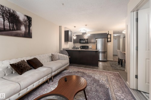 Living area featuring dark wood-type flooring and a textured ceiling - 205 340 Windermere Road, Edmonton, AB - Indoor Photo Showing Living Room