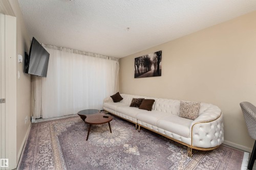 Living room with a textured ceiling and baseboards - 205 340 Windermere Road, Edmonton, AB - Indoor Photo Showing Living Room
