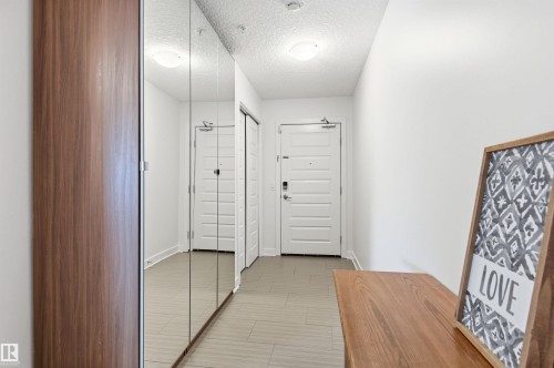 Corridor with a textured ceiling and baseboards - 106 1238 Windermere Way, Edmonton, AB - Indoor Photo Showing Other Room