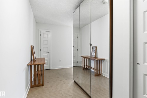Hallway featuring a textured ceiling and baseboards - 106 1238 Windermere Way, Edmonton, AB - Indoor Photo Showing Other Room