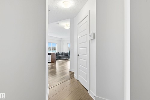 Hall with a textured ceiling and wood tiled floors - 106 1238 Windermere Way, Edmonton, AB - Indoor Photo Showing Other Room