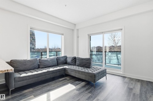 Living area with baseboards and wood finished floors - 106 1238 Windermere Way, Edmonton, AB - Indoor Photo Showing Living Room