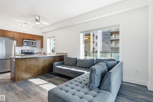 Living room featuring a ceiling fan and dark wood finished floors - 106 1238 Windermere Way, Edmonton, AB - Indoor
