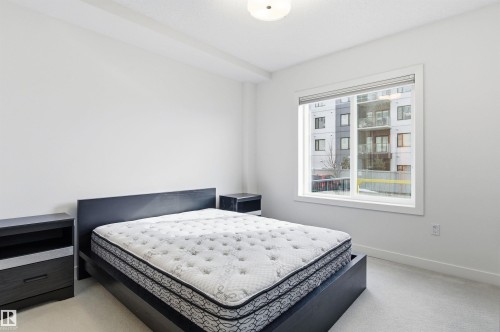 Bedroom with light carpet and baseboards - 106 1238 Windermere Way, Edmonton, AB - Indoor Photo Showing Bedroom