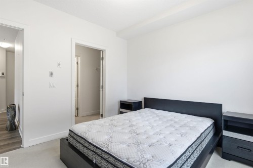Bedroom with light carpet and baseboards - 106 1238 Windermere Way, Edmonton, AB - Indoor Photo Showing Bedroom