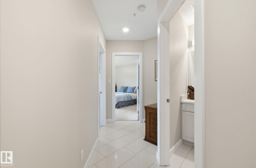 Hallway with baseboards and light tile patterned floors - 309 625 Leger Way, Edmonton, AB - Indoor Photo Showing Other Room