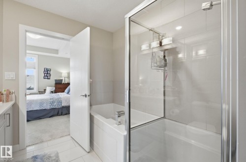 Bathroom featuring vanity, ensuite bath, a garden tub, a shower stall, and light tile patterned floors - 309 625 Leger Way, Edmonton, AB - Indoor Photo Showing Bathroom